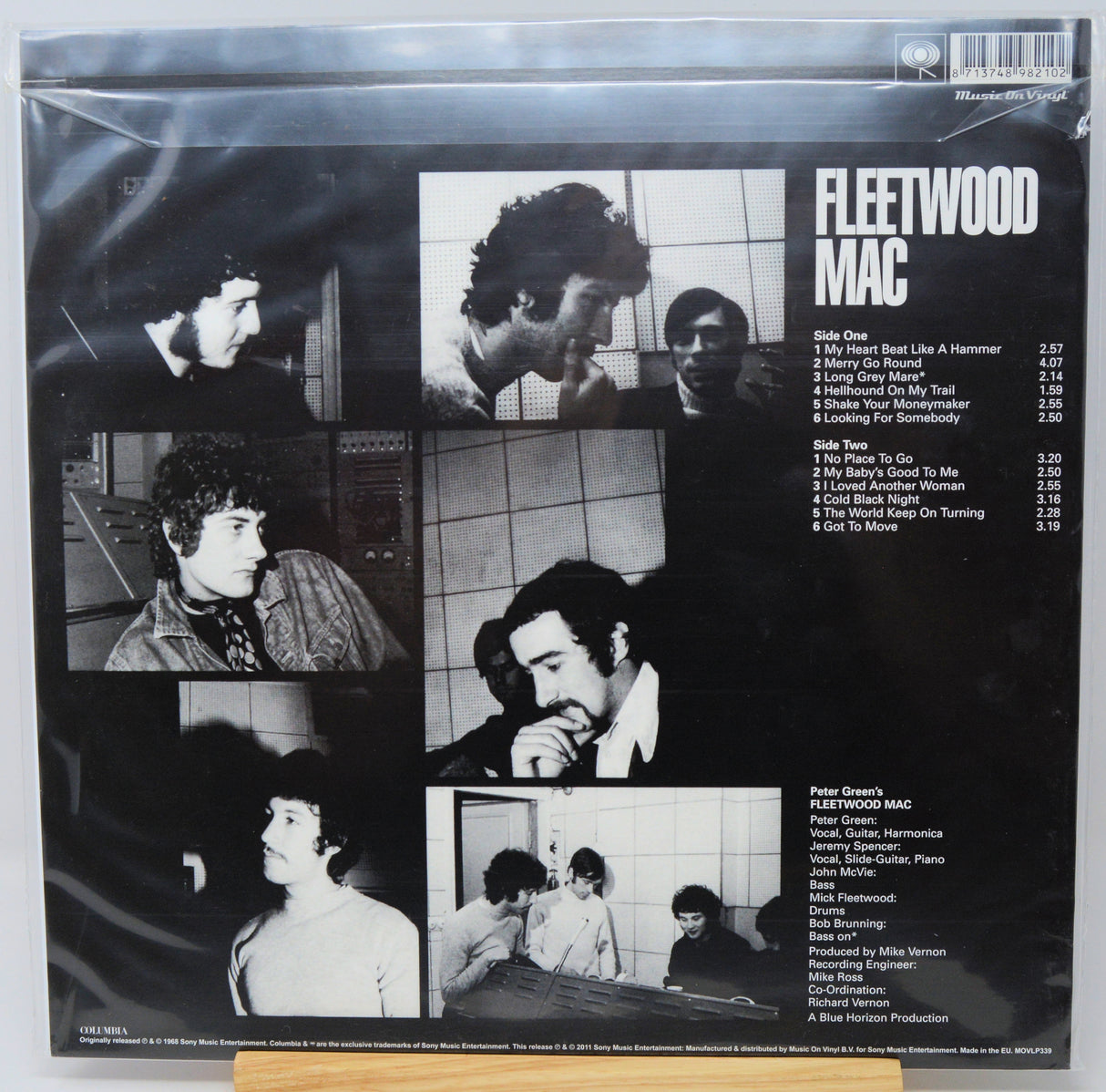 The back cover of a Fleetwood Mac vinyl record, sealed in a plastic shrink wrap. The black cover features multiple black-and-white photos of the band members, the tracklist on the right, and the title 'FLEETWOOD MAC' in bold white text.