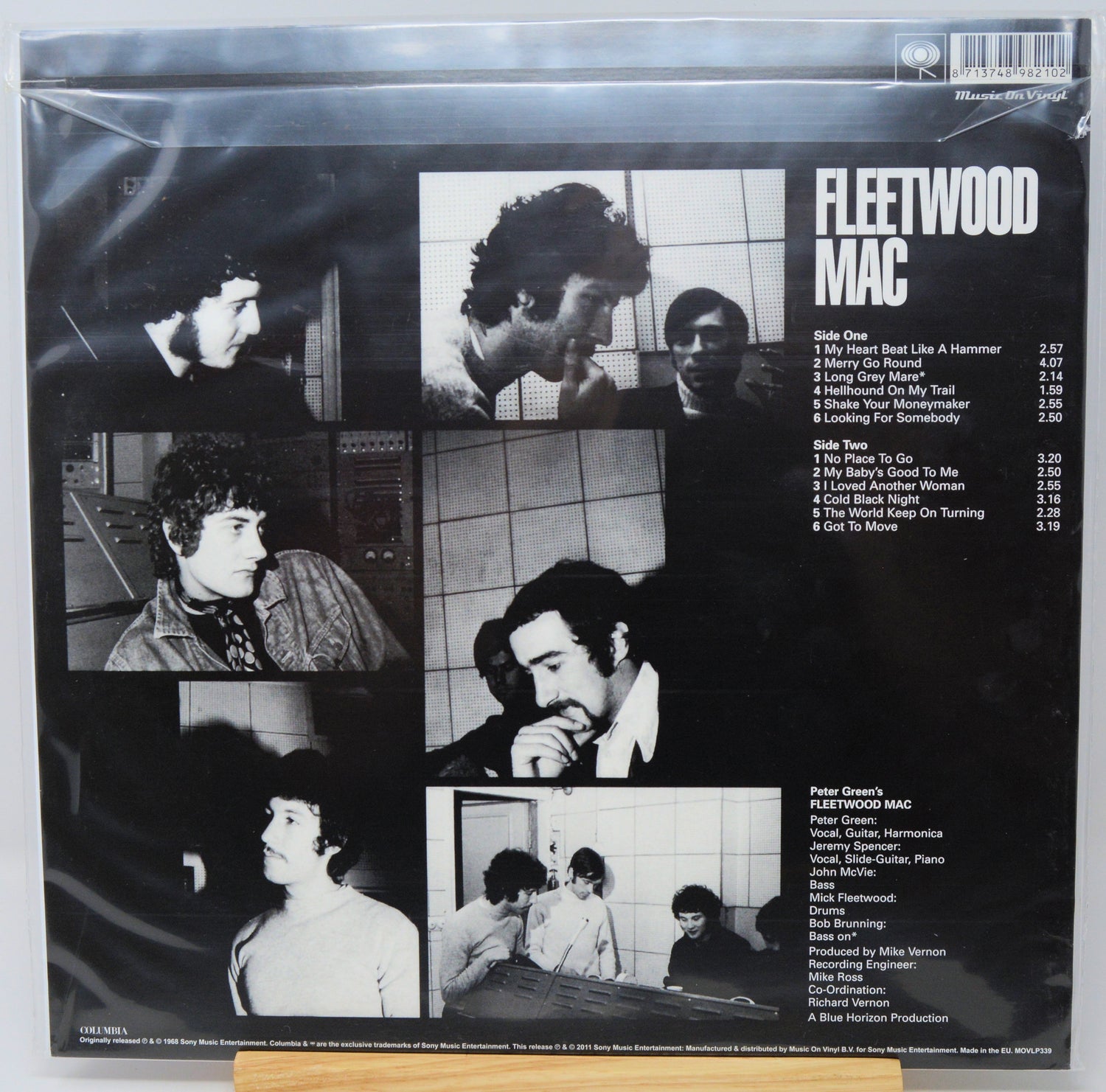 The back cover of a Fleetwood Mac vinyl record, sealed in a plastic shrink wrap. The black cover features multiple black-and-white photos of the band members, the tracklist on the right, and the title 'FLEETWOOD MAC' in bold white text.