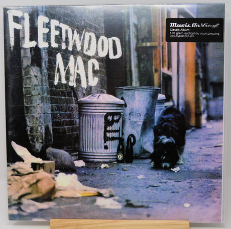 Fleetwood Mac 'Rumours' vinyl record album cover shown flat against a light background, with the band name in large white letters over a street scene featuring trash cans, a dog, and debris. A 'Music On Vinyl' sticker is visible in the top right.