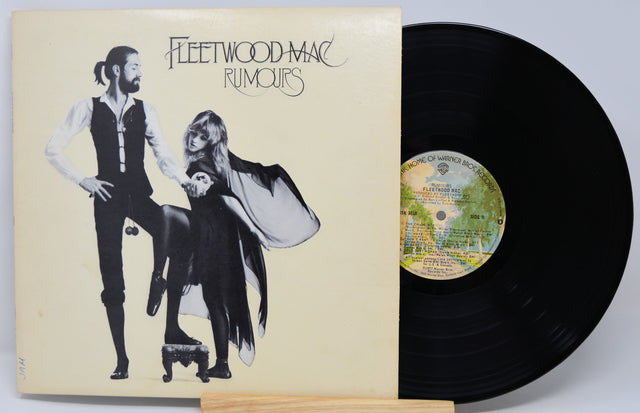 Fleetwood Mac 'Rumours' vinyl record album with the illustrated sleeve cover partially covering a black LP record on a light gray background.