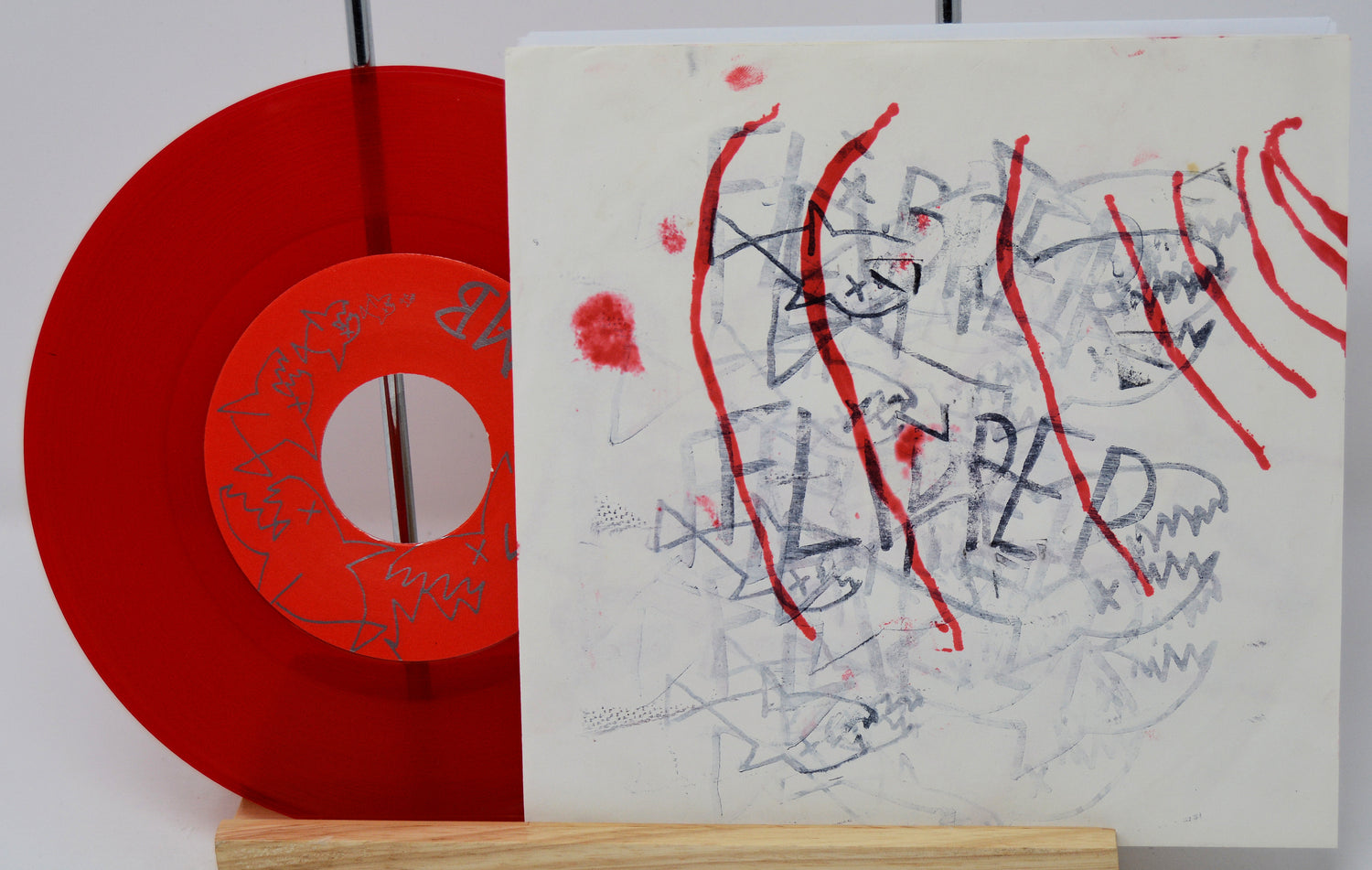 Red vinyl record with a white label featuring abstract art and text.