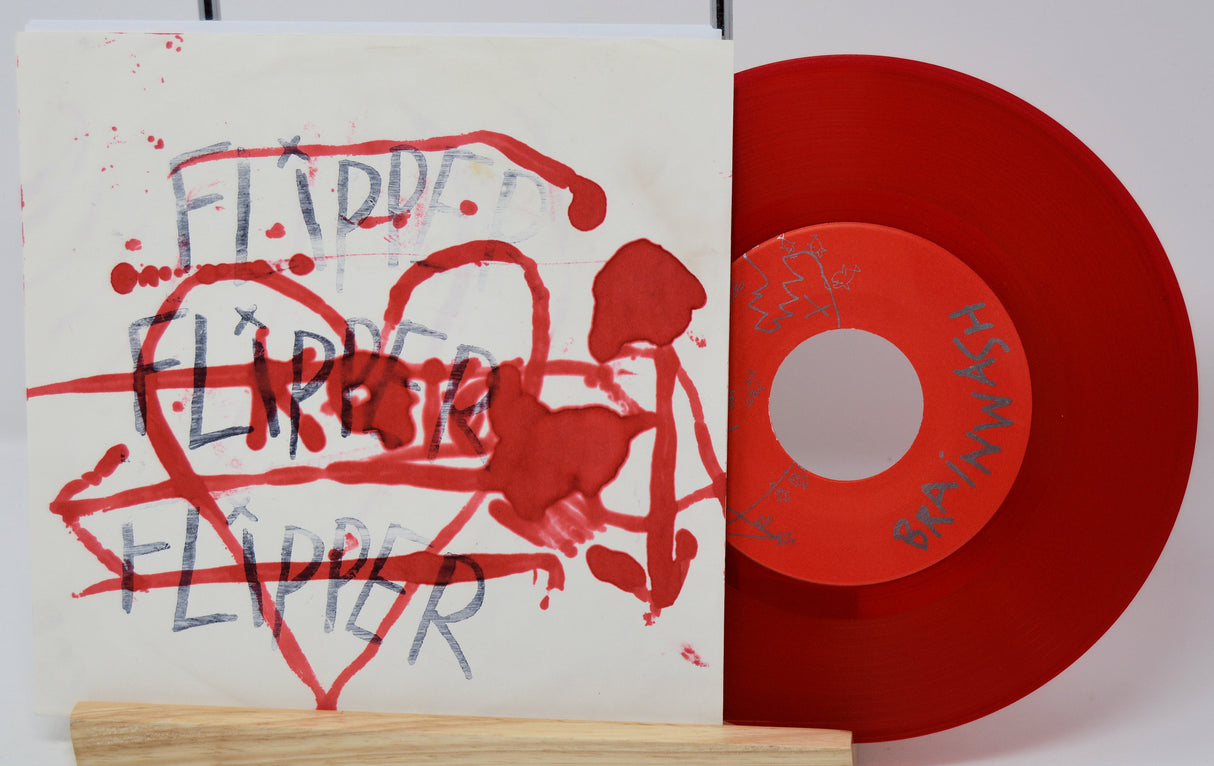 Red vinyl record with a white label and a sleeve featuring red and black text and graphics.