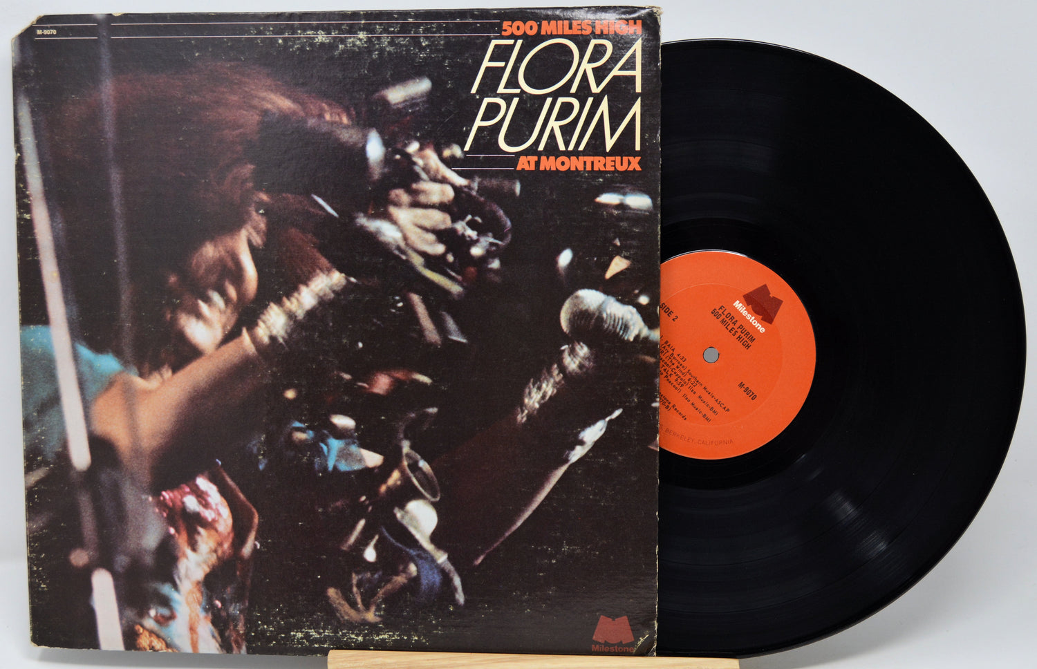 Vinyl record album '500 Miles from Hell' by Flora Purim, showing the illustrated cover on the left and the black record partially pulled out on the right against a light gray background.