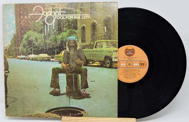 Vinyl record with cover featuring a statue and cityscape