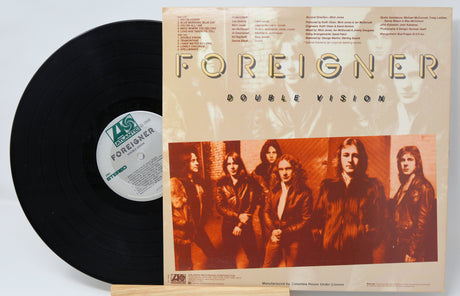 A used vinyl record of Foreigner's album 'Double Vision' with the band members pictured on the  back cover with text for the song titles.