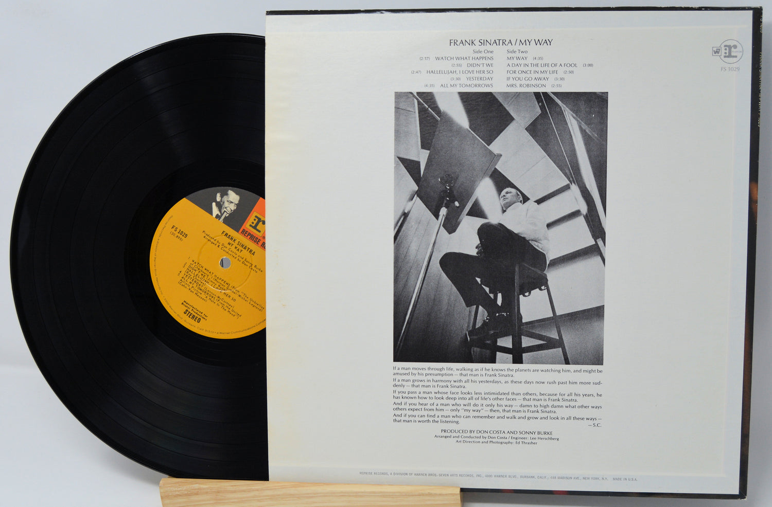 Album cover with artistic illustrations of people and landscapes, featuring a prominent figure with a gold chain.