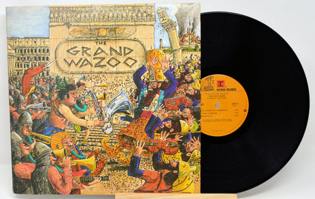 The Grand Wazoo vinyl record album with its illustrated cover jacket and a black LP partially visible behind it on a light gray background.