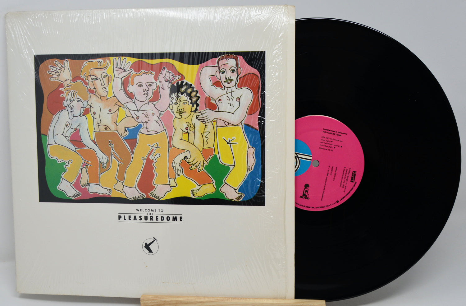 Vinyl record with colorful cover featuring people and a pink label on a white background