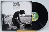 A vinyl record titled 'Gary Clark Jr Live' with an image of a man playing a guitar on the cover, in front of a crowd. The record is on a white background.
