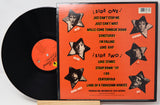 Vinyl record with orange cover featuring star-shaped cutouts of a person's face and text.