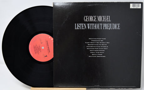A vinyl record partially pulled from its black sleeve, showing the back cover with the title 'George Michiel Listen Without Prejudice' in white text. The record has a pink-orange center label.