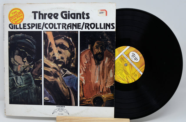Vinyl record with cover featuring illustrations of musicians and text 'Three Giants' by Gillespie/Coltrane/Rollins.