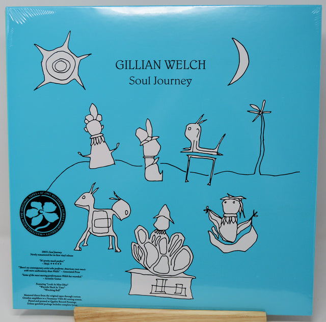Gillian Welch - Soul Journey vinyl record cover, showing the blue back of the sleeve with hand-drawn black line illustrations and text, displayed on a wooden stand.