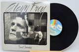 Glenn Frey 'Soul Searchin'' vinyl record with the album cover standing next to the black LP record on a small wooden stand against a white background.