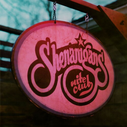 Pink neon sign with 'Shenanigans Nite Club' text against a blurred background