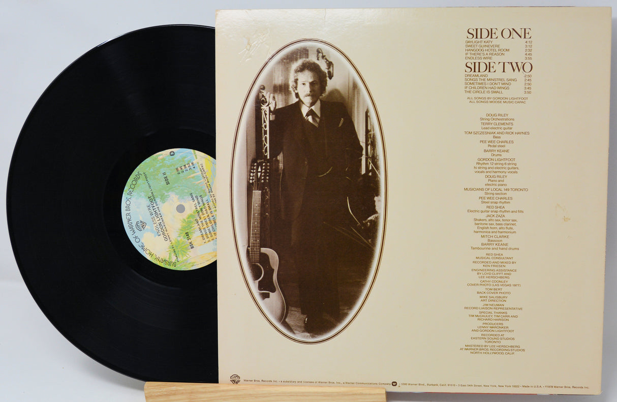 Vinyl record with cover featuring a portrait and album details on a light gray background