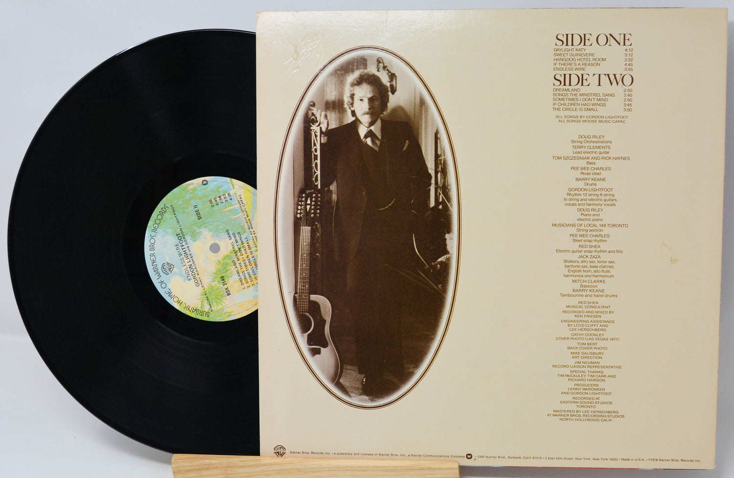 Vinyl record with cover featuring a portrait and album details on a light gray background