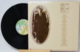 Vinyl record with cover featuring a portrait and album details on a light gray background