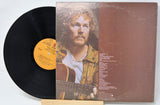 Vinyl record with a cover featuring a person playing guitar on a white background