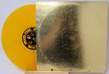 Vinyl record with a yellow disc and gold cover featuring a black and white portrait.