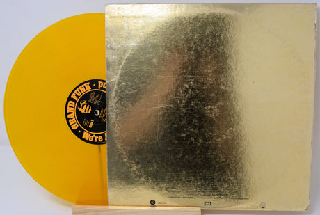 Vinyl record with a yellow disc and gold cover featuring a black and white portrait.