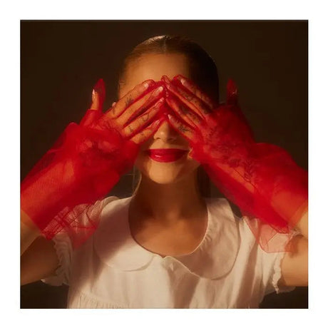 Ariana Grande with red vinyl gloves covering her eyes, wearing a white shirt.