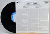A vinyl record partially pulled from its back cover sleeve, showing the black record on the left and the printed back of the album case on the right. The cover reads 'Grant Green - Born to Be Blue' with track listing and copyright details.