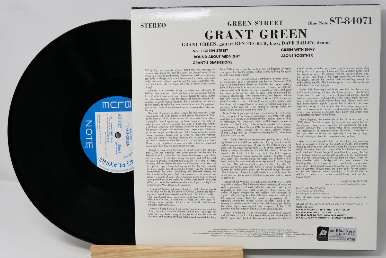 A vintage vinyl record album shown with the black record partially pulled from its white paper sleeve. The sleeve features the title 'GRANT GREEN - Green Street' and dense printed track information, with a blue circular label on the record.