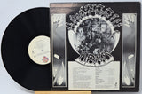 A vinyl record partially pulled from its sleeve, showing the black record, cream center label, and black-and-white album cover with stylized text and floral side panels.