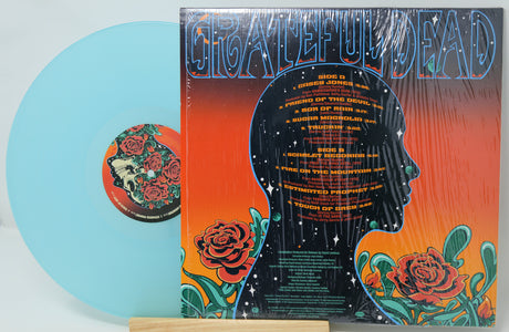 Vinyl record with a colorful cover featuring a silhouette and floral designs, on a light gray background.