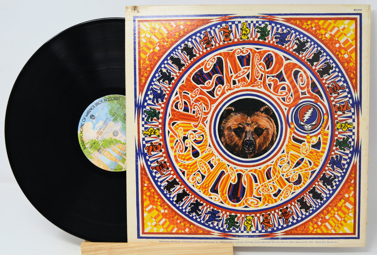 A vinyl record partially pulled from its illustrated album sleeve, showing the black record and the cover art for Jim Morrison's 'Rumours'. The sleeve features a highly detailed, colorful mandala-style design with a bear in the center and the band's name in stylized lettering.