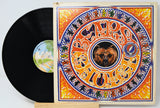 A vinyl record partially pulled from its illustrated album sleeve, showing the black record and the cover art for Jim Morrison's 'Rumours'. The sleeve features a highly detailed, colorful mandala-style design with a bear in the center and the band's name in stylized lettering.