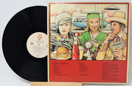 Vinyl record with a colorful cover featuring three people and a burger, on a light gray background.