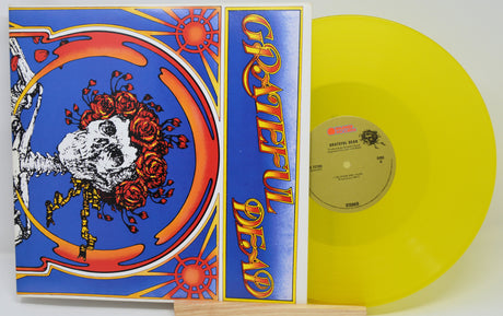 Vinyl record with a colorful cover featuring a skeleton and roses, on a white background.