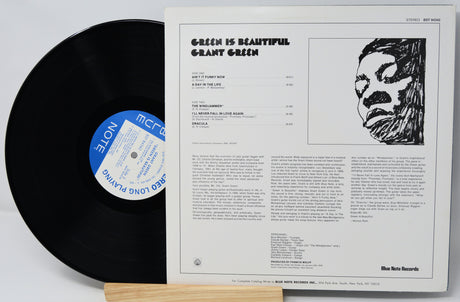 Vinyl record with its cover displaying text and a face illustration on a light gray background