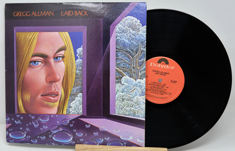 Vinyl record with cover featuring a portrait and nature scene, on a white background