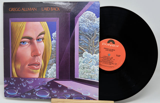 Vinyl record with cover featuring a portrait and nature scene, on a white background