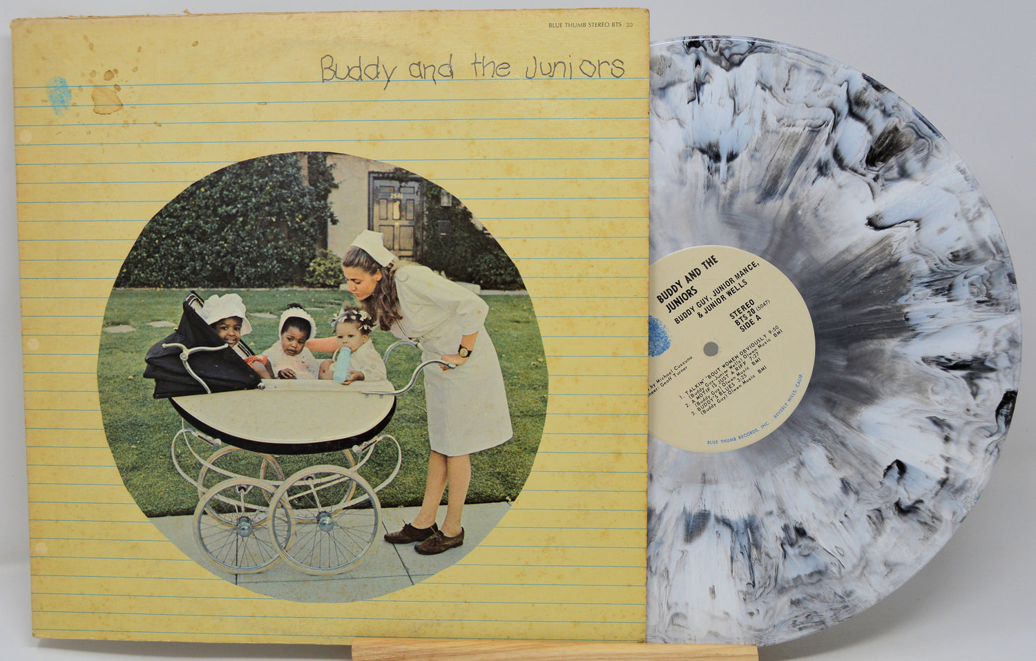 Vinyl record with cover featuring a woman and children around a baby carriage, on a yellow background.