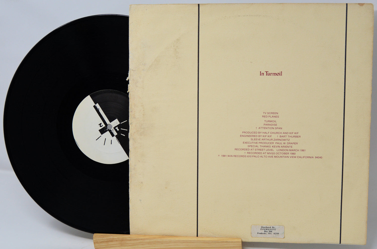 Vinyl record with a black label and beige sleeve on a light gray background