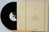 Vinyl record with a black label and beige sleeve on a light gray background