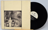 Vinyl record with cover featuring a black and white illustration of a person in a room.