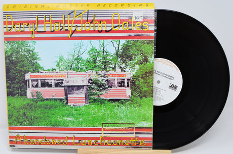 Vinyl record with a cover featuring an abandoned lunch counter and trees.