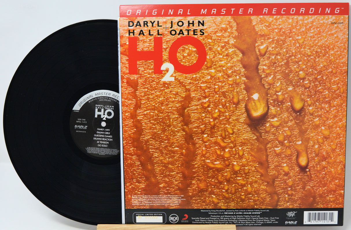 Vinyl record album shown with the black record partially pulled from the cover, which features the title 'H2O' and artist Daryl John Hall Oates on a textured orange background with water droplets.