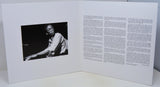 Open book with a black and white photo on one side and text on the other, on a white background.
