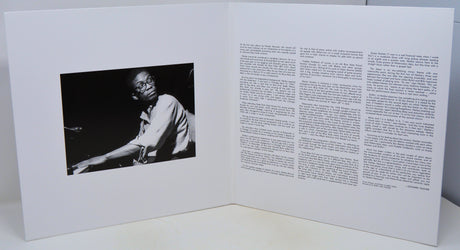 Open book with a black and white photo on one side and text on the other, on a white background.