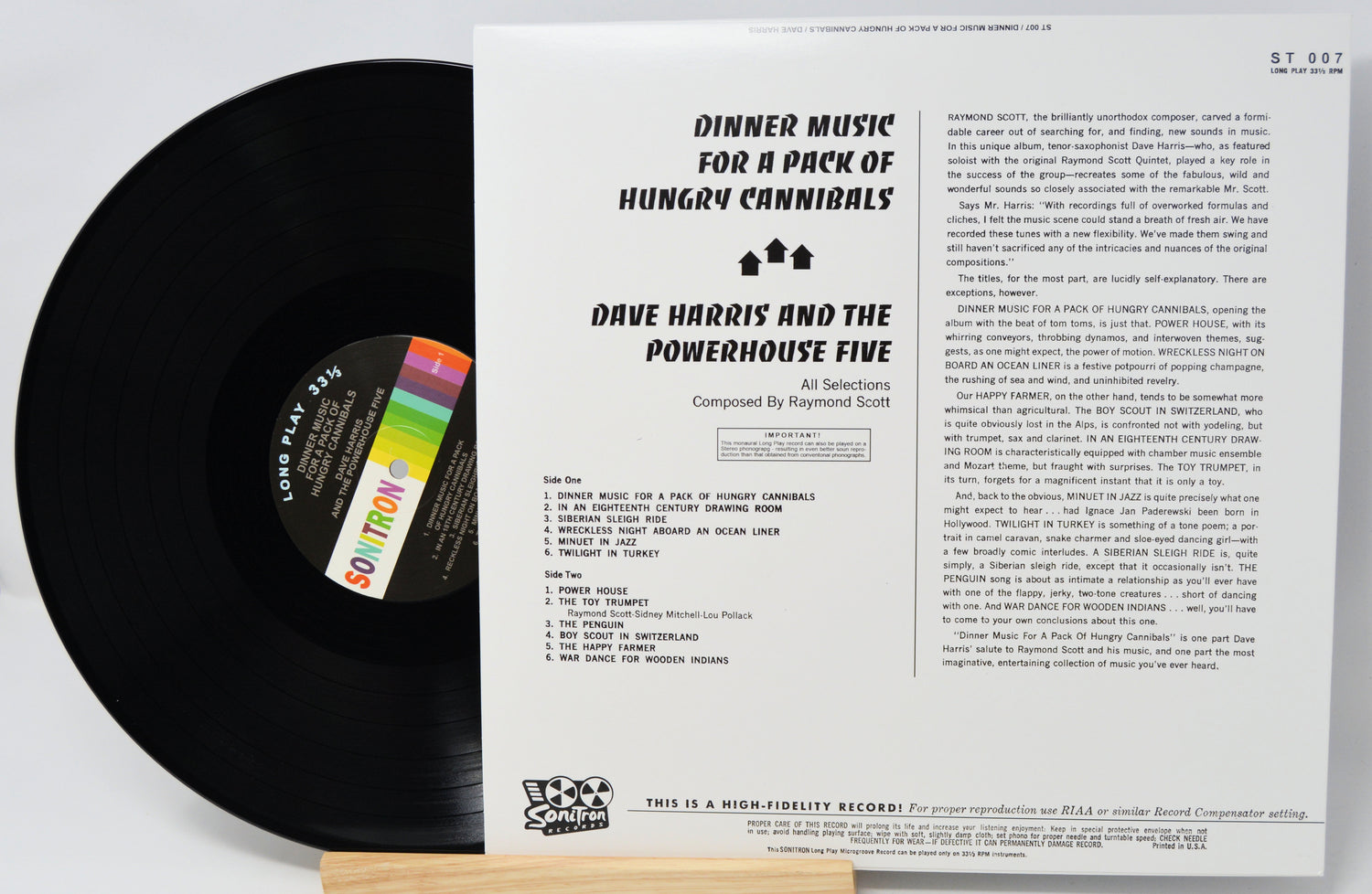 Vinyl record with cover displaying text and a colorful label on a light gray background