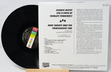Vinyl record with cover displaying text and a colorful label on a light gray background