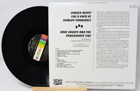 Vinyl record with cover displaying text and a colorful label on a light gray background