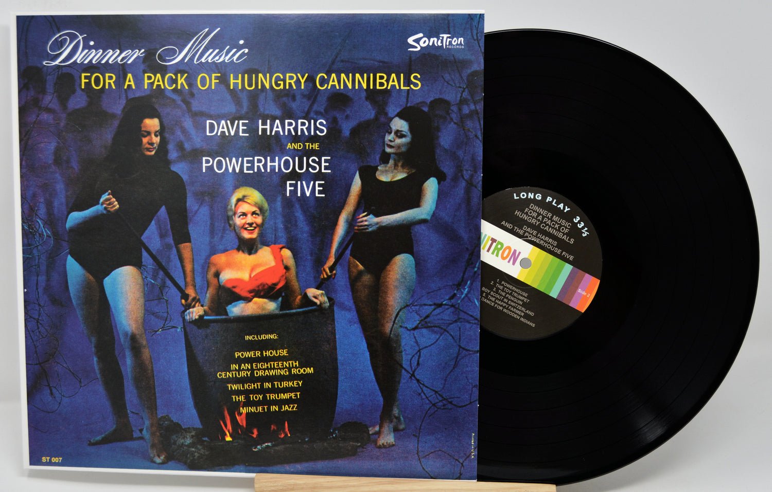 Vinyl record with cover featuring three people around a drum, on a white background