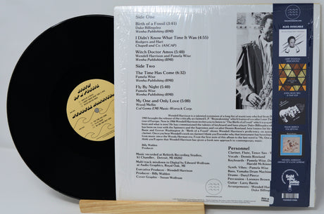 Vinyl record with black disc and white label on a stand, showing text and a small yellow label.